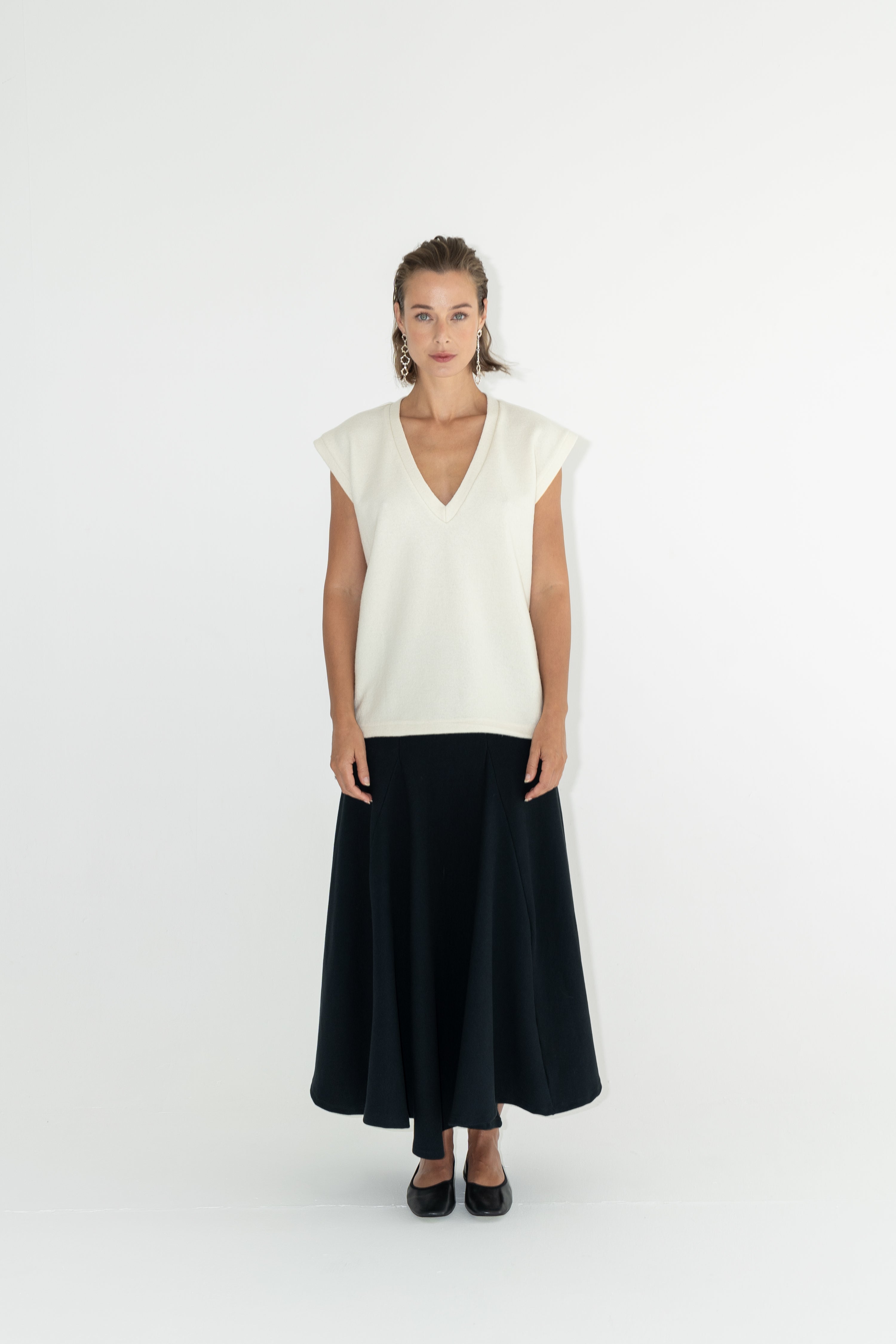 Modelka v sukni z organické bavlny v černé barvě a off-white vestě z merino vlny ADVA Studios.