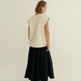 Modelka v sukni z organické bavlny v černé barvě a off-white vestě z merino vlny ADVA Studios.