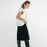 Model in black turtleneck dress with merino white vest.