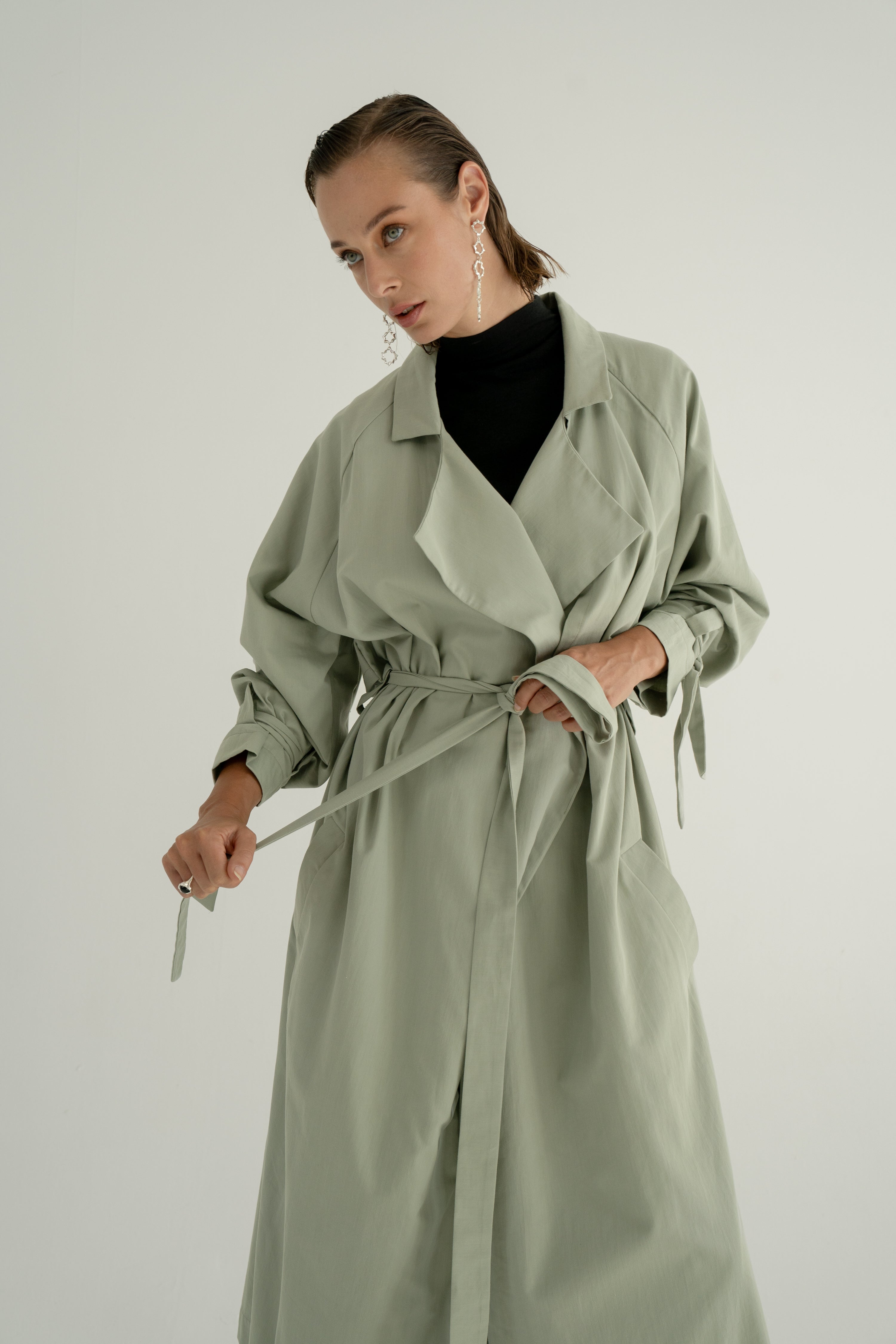 ADVA Studios Olive Green Trenchcoat from organic cotton with black turtleneck.