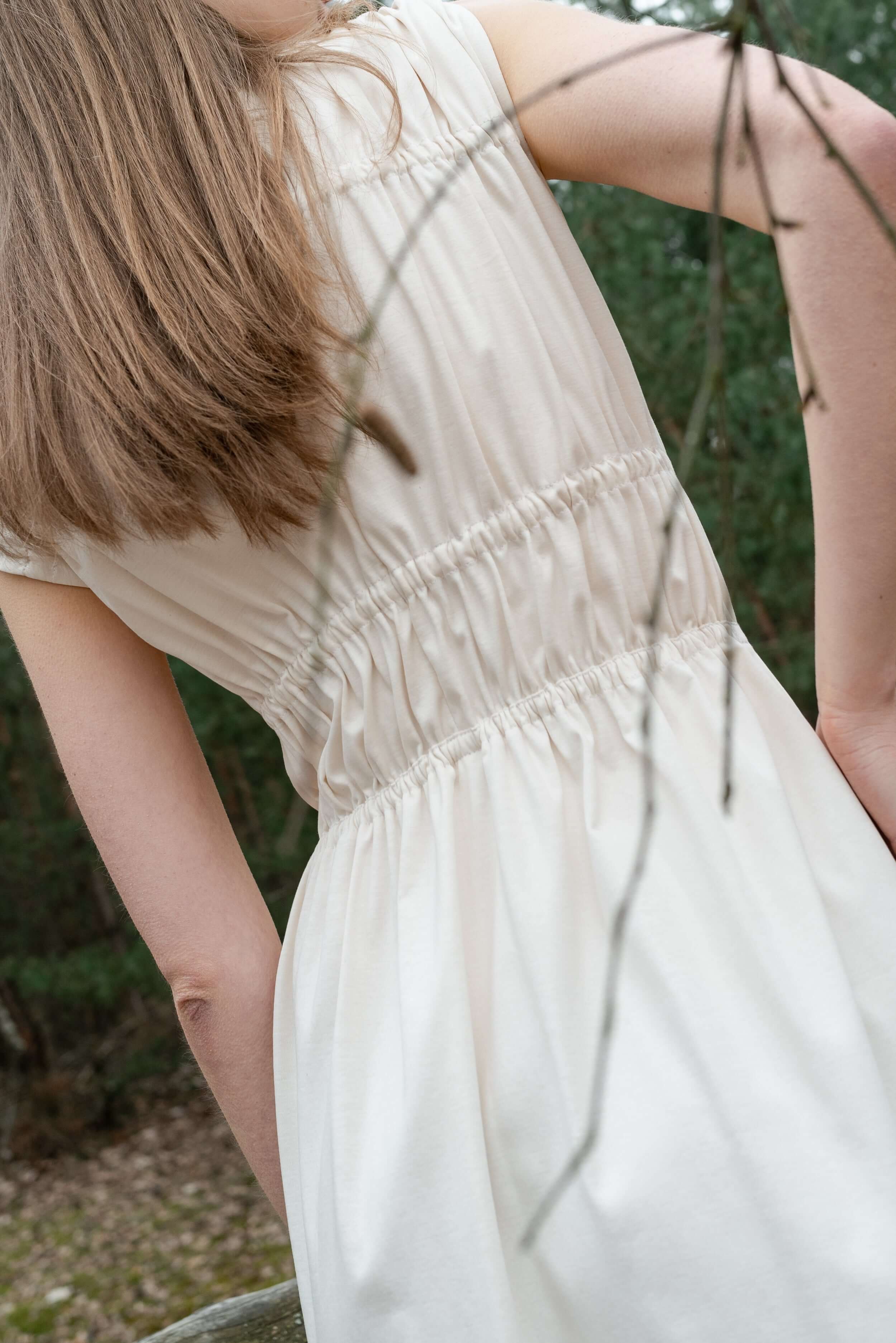 detail krémových nařasených šatů z organické bavlny