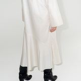 Dámské bílé dlouhé šaty z organické bavlny s výraznými černými koženými botami.