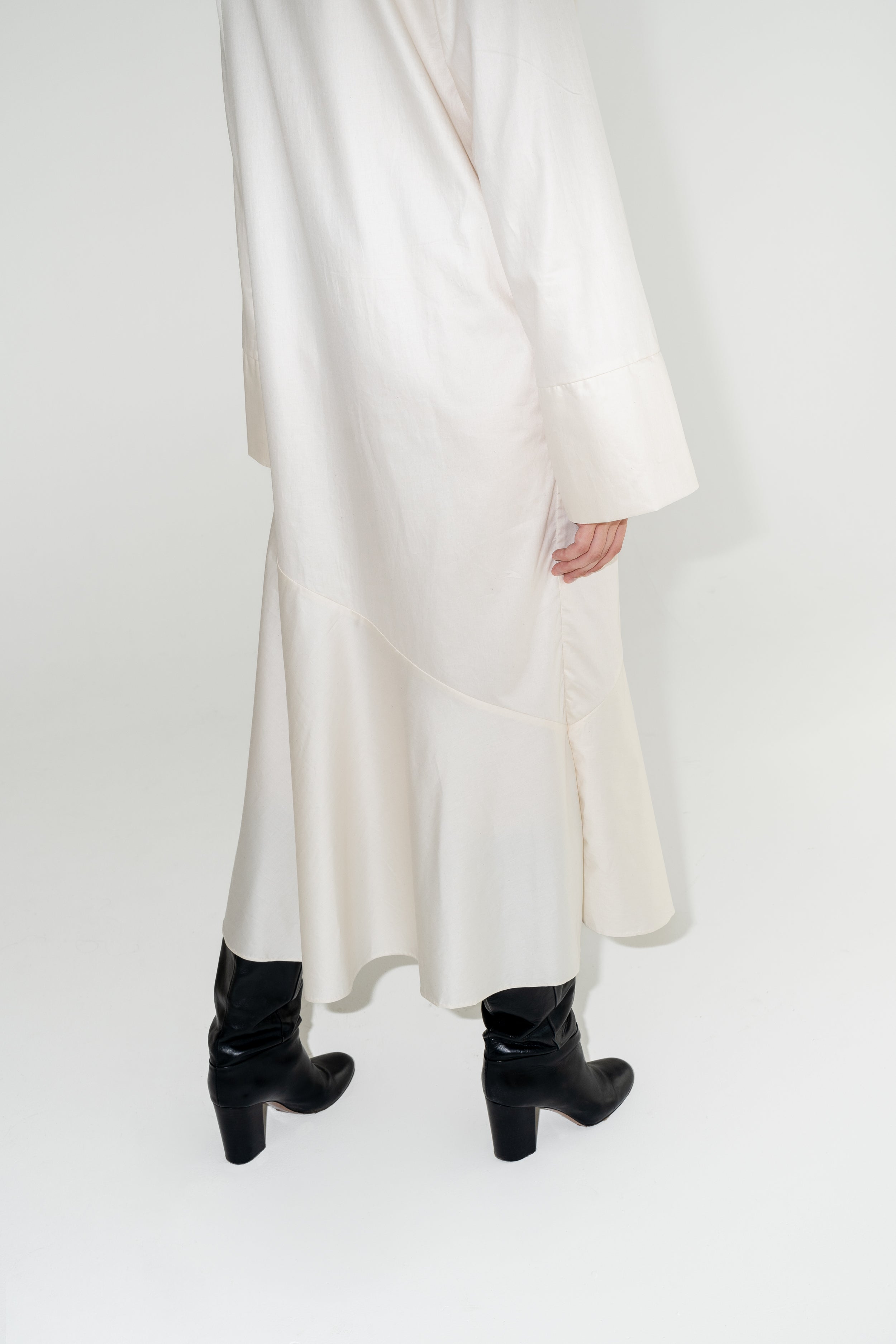 Dámské bílé dlouhé šaty z organické bavlny s výraznými černými koženými botami.