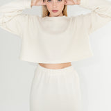 Oversized boxy bílý dámský svetr s širokými rukávy z organické merino vlny s dlouhou bílou sukní. 