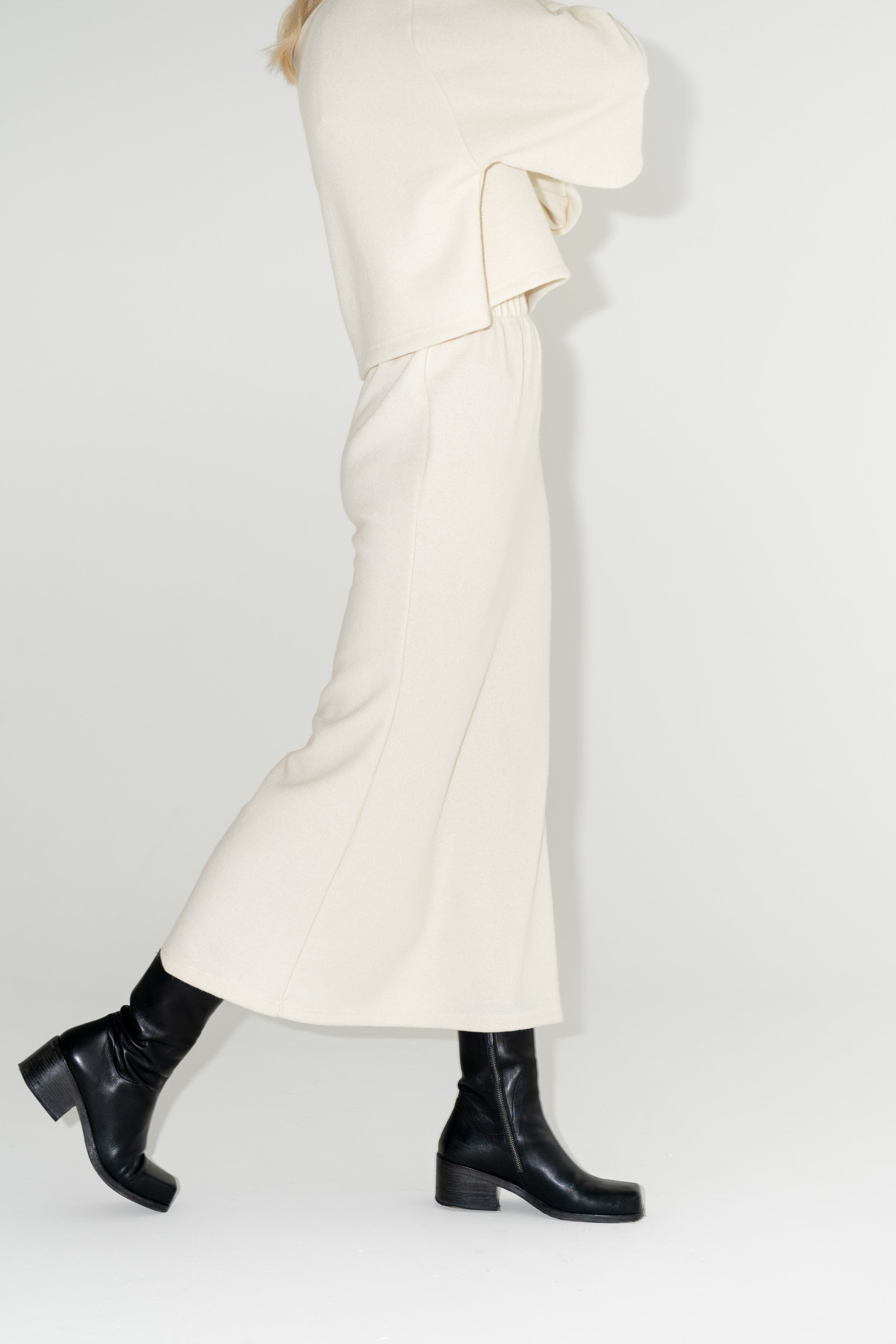 Dámská bílá sukně ke kotníkům z organické merino vlny s černými kozačkami. ADVA Studios