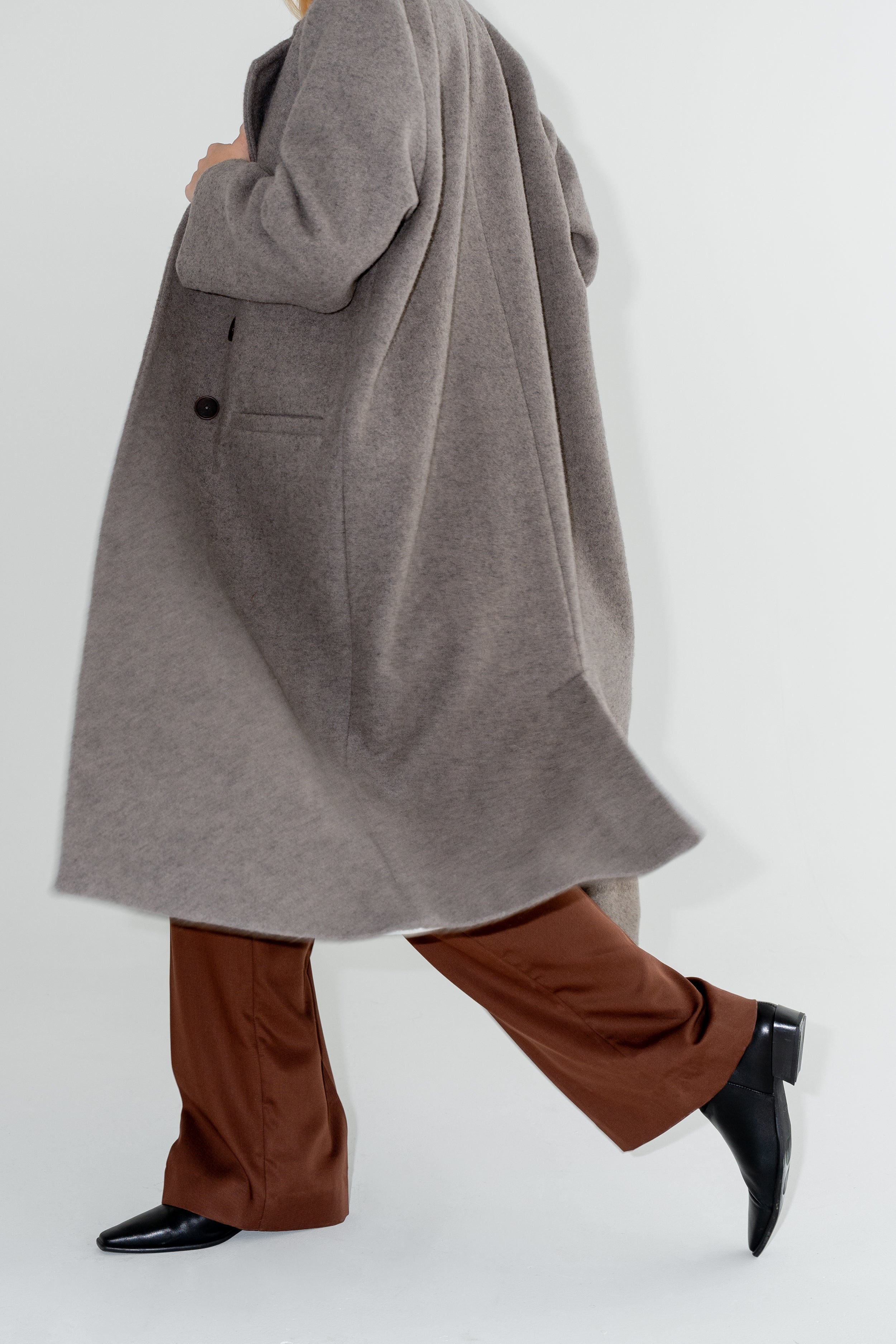 Dámský oversized dvouřadý kabát z organické vlny. Zimní Kabát Beyond Ordinary má dvouřadý oversized střih, čisté linie a výrazné knoflíky s hnědými širokymi kalhotami. ADVA Studios