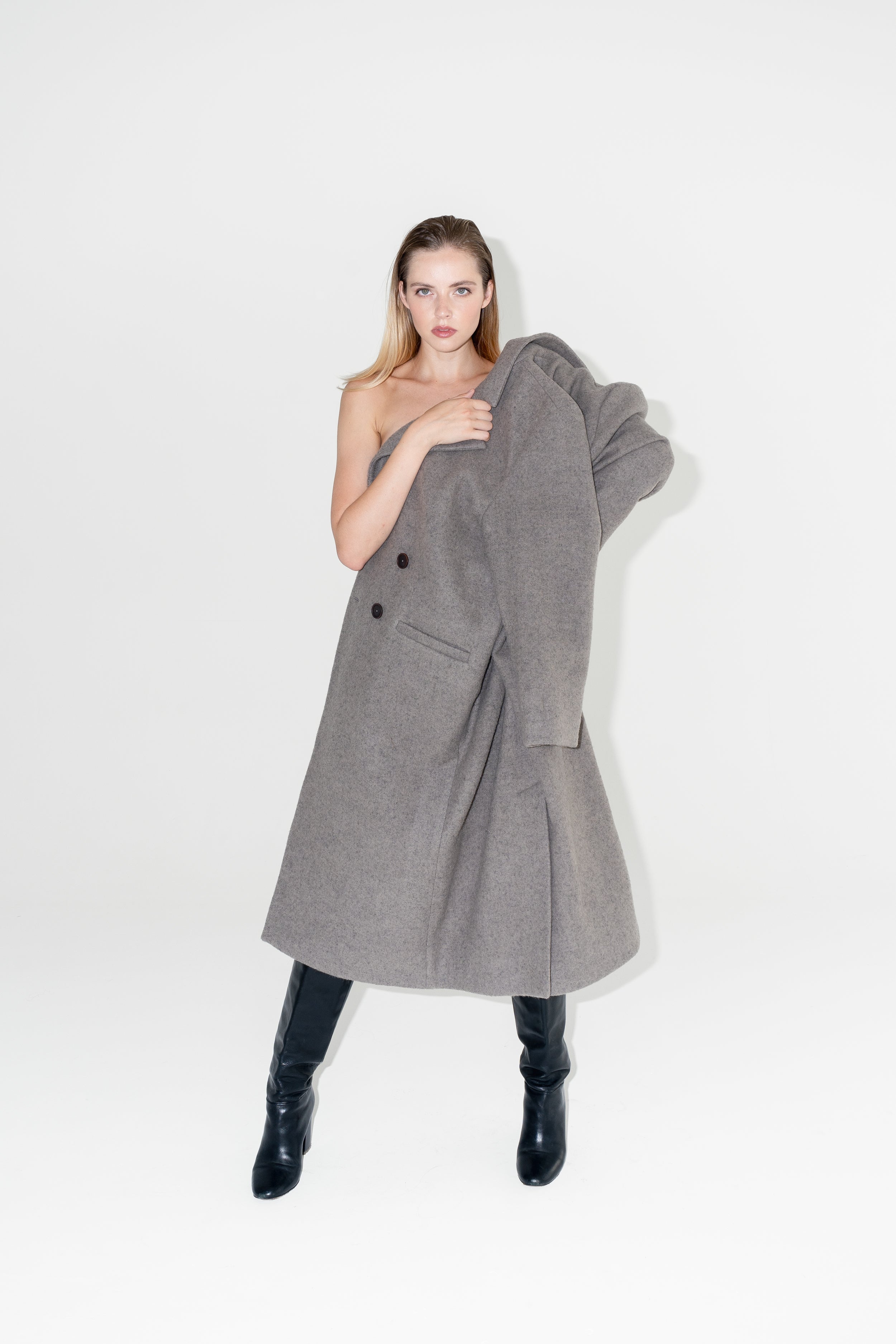 Dámský oversized dvouřadý kabát z organické vlny. Zimní Kabát Beyond Ordinary má dvouřadý oversized střih, čisté linie a výrazné knoflíky s černými kozačkami na podpatku. ADVA Studios