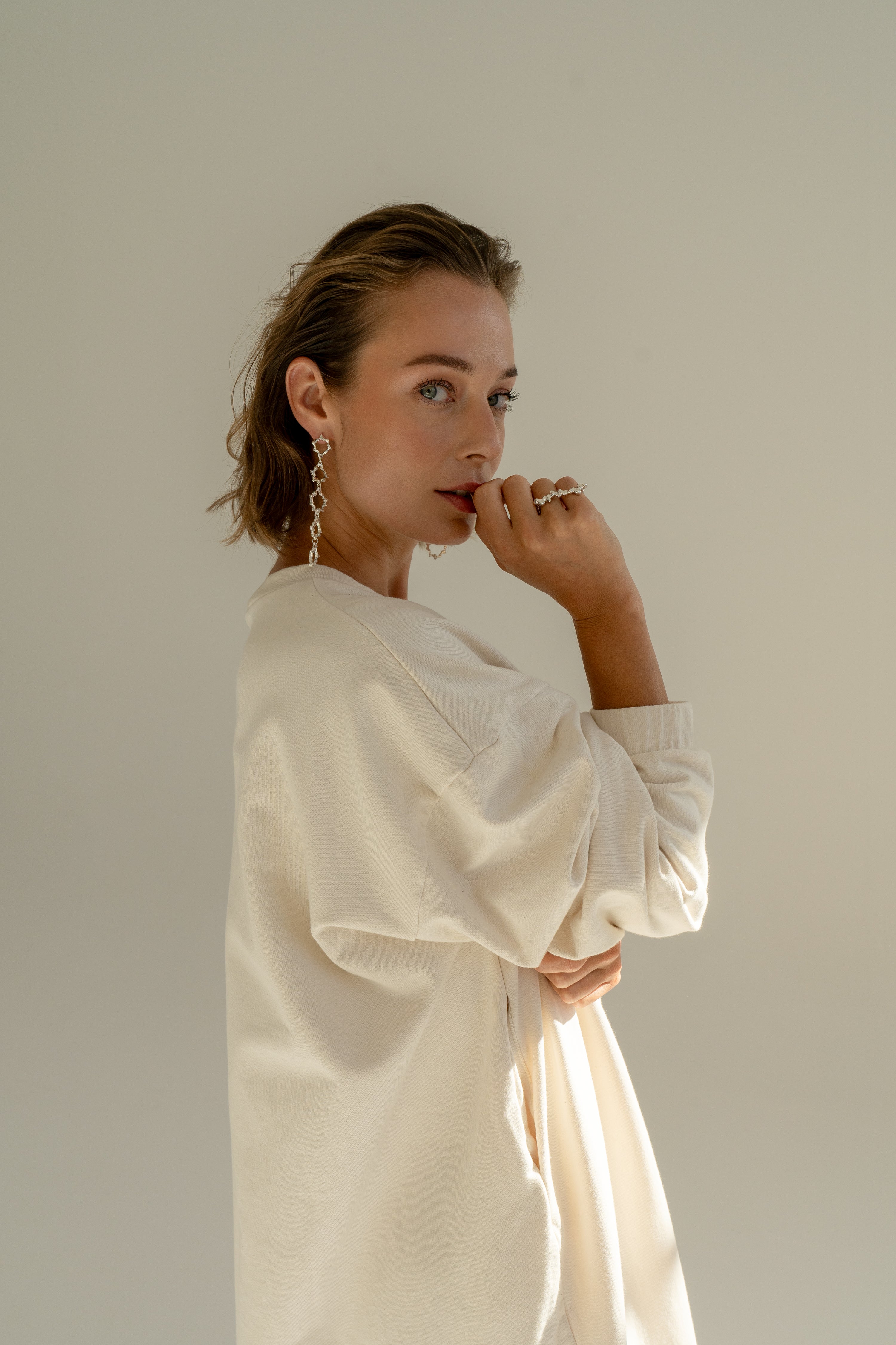 Model in oversized sweatshirt dress in offwhite color.