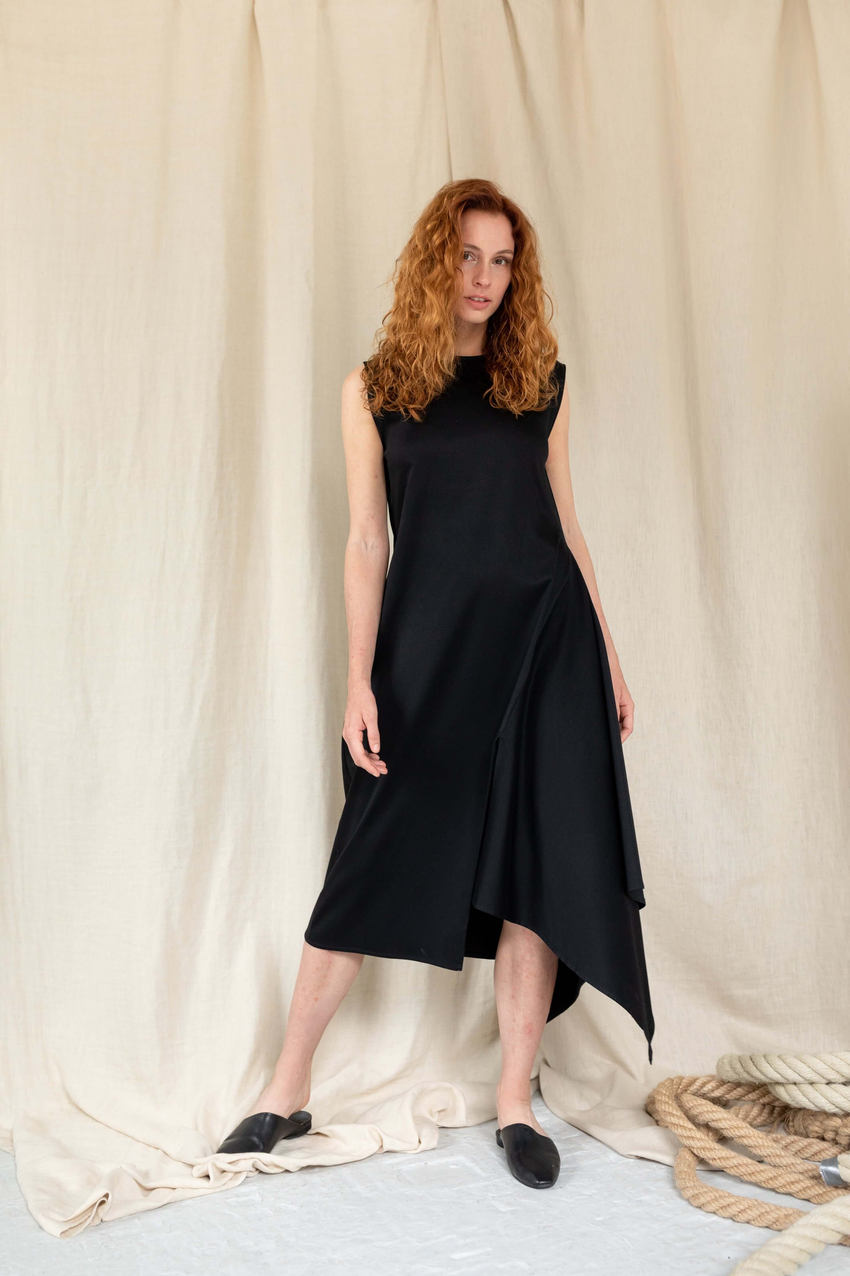 Černé asymetrické midi Win It šaty bez rukávů s vysokým rozparkem. Jsou vyrobeny z 100% GOTS certifikované bavlny. Moderní, elegantní a sofistikované. ADVA Studios