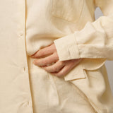 Detail lněné košile a lněných kraťas ADVA Studios ve světle vanilkové barvě. 